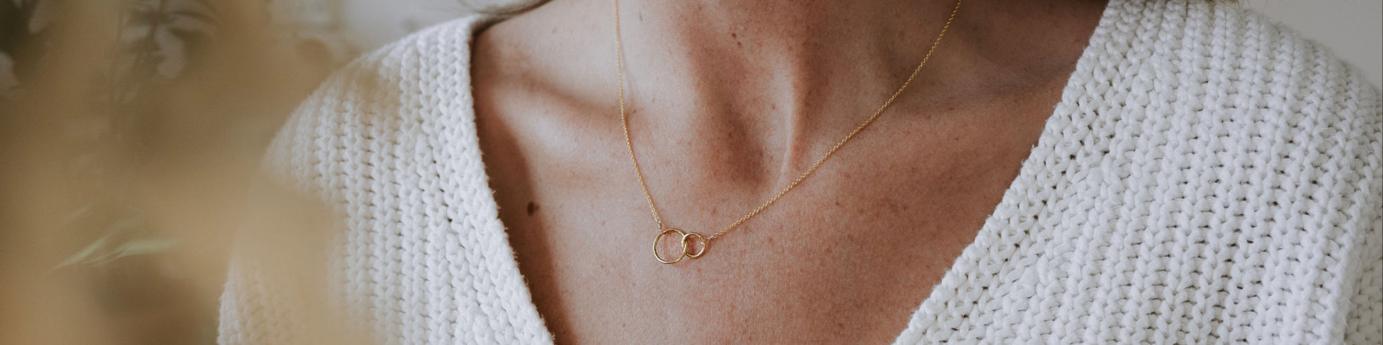Close-up of a golden crescent moon pendant on a necklace resting against a person's neck.
