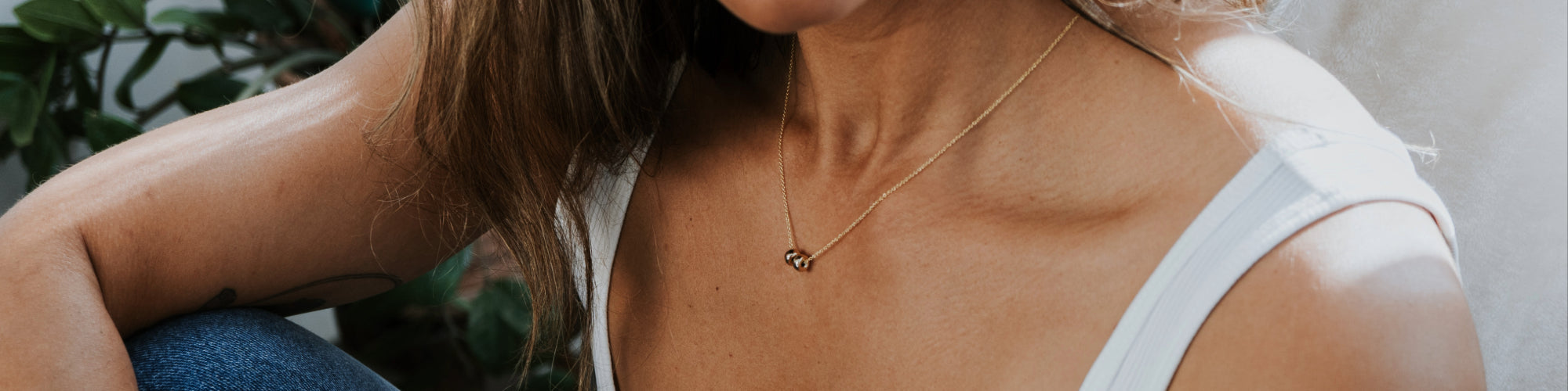 Close-up of a woman wearing a white cardigan and a delicate necklace with a circular pendant.