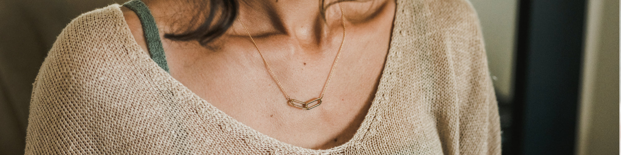 Gold musical note pendant on a necklace against a person's neckline.