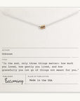 Close-up of a card showcasing the Three Things Necklace from Becoming Jewelry, featuring three rings and an inspirational quote: "In the end, only three things matter: how much you loved, how gently you lived, and how gracefully you let go of things not meant for you." This message encourages embracing life with love and grace.