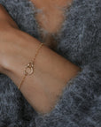 Woman wearing a gold bracelet and earrings, with a neutral background