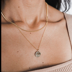 A close-up of a woman's neck showing a Curb Chain Necklace with a pendant from Becoming Jewelry.