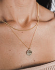 A close-up of a woman's neck showing a Curb Chain Necklace with a pendant from Becoming Jewelry.