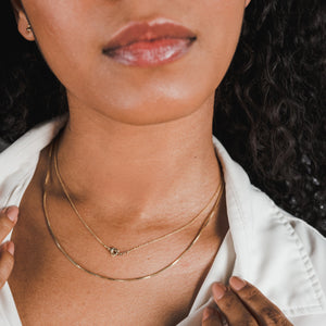 Close-up of a woman wearing a white shirt and Becoming Jewelry's Love Knot Necklace.