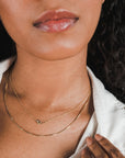 Close-up of a woman wearing a white shirt and Becoming Jewelry's Love Knot Necklace.