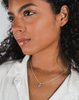 Woman wearing a Believe in Magic Necklace by Becoming Jewelry with a blue pendant.
