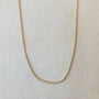 A delicate gold Bead Chain Necklace from Becoming Jewelry displayed on a neutral background, showcasing its intricate texture.