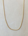 A delicate gold Bead Chain Necklace from Becoming Jewelry displayed on a neutral background, showcasing its intricate texture.