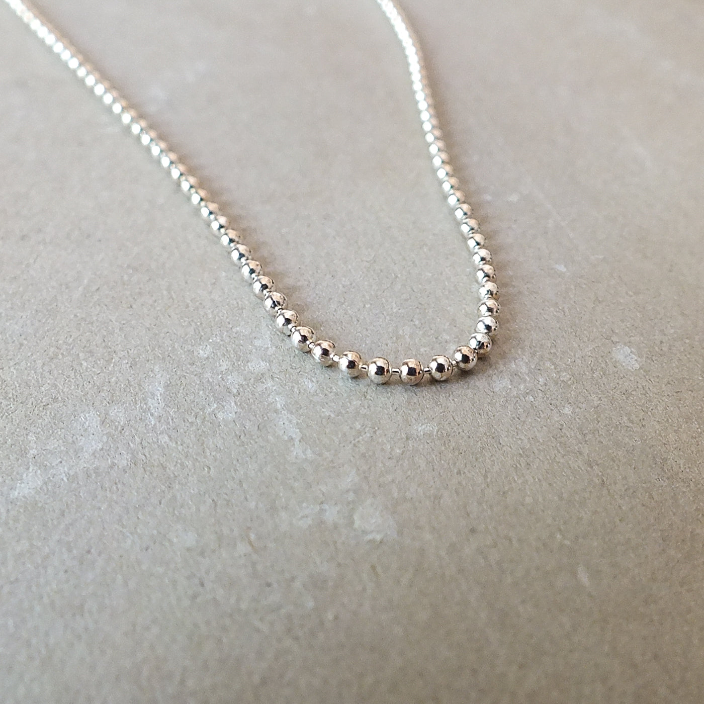 Becoming Jewelry&#39;s Sterling Silver Bead Chain Necklace on a light gray surface.