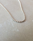 Close-up of the Becoming Jewelry Bead Chain Necklace laid out flat on a light-colored surface, showcasing its intricate silver texture.