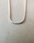 A Becoming Jewelry sterling silver box chain necklace laid out on a textured surface.