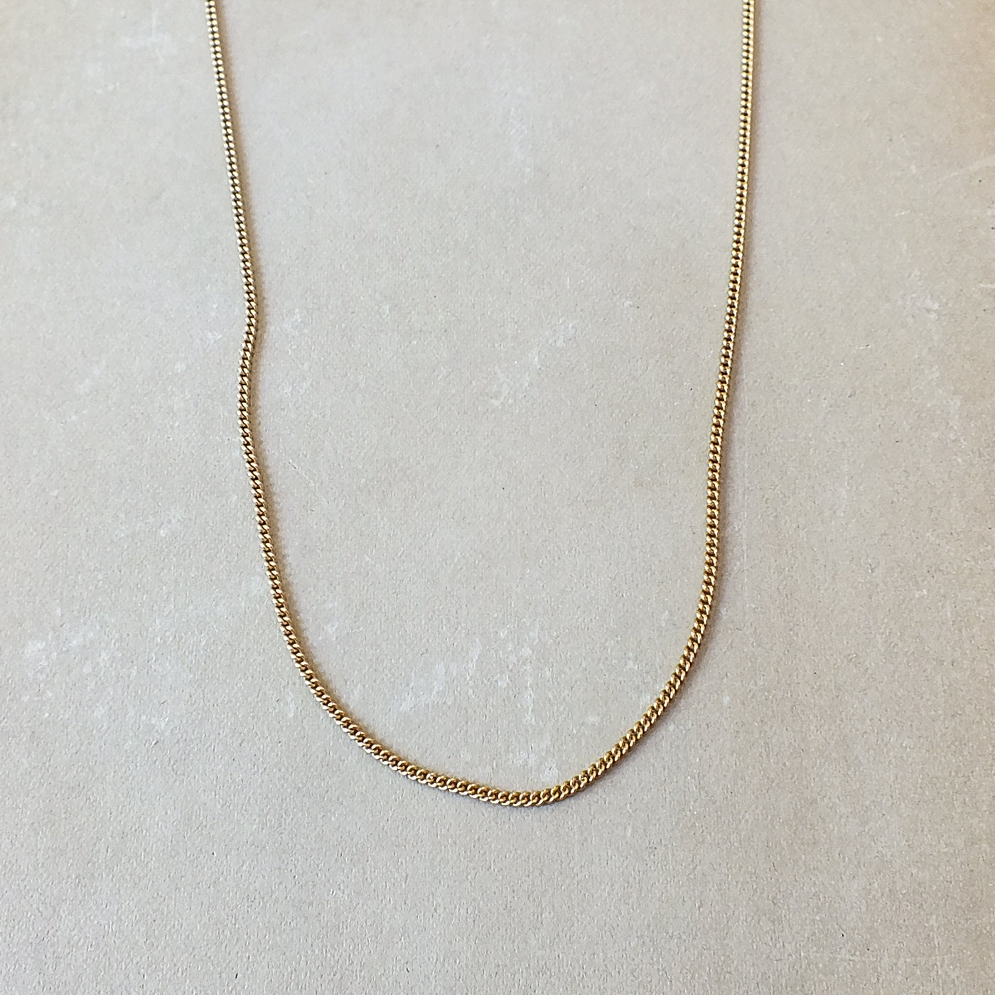 Becoming Jewelry Gold filled curb chain necklace on a pale background.