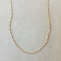 A delicate Becoming Jewelry Figaro Chain Necklace, crafted with small, interlinked oval links, displayed on a light beige surface.