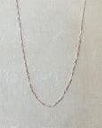 Gold filled Becoming Jewelry Figaro chain necklace on a textured grey background.