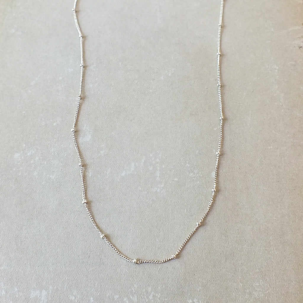 Becoming Jewelry's sterling silver Satellite Chain Necklace is featured on a gray background.