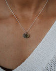 Necklace with heart-shaped pendants worn by a person in a white textured garment.