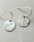 A pair of Becoming Jewelry Hammered Disc Drop Earrings, small displayed on a gray background.
