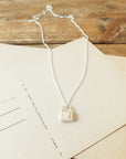 Hidden Treasures Necklace by Becoming Jewelry with a padlock pendant displayed on a beige card.