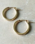 A pair of Becoming Jewelry Everyday Hoop Earrings, large on a gray surface.