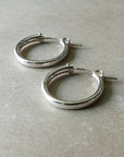 A pair of Becoming Jewelry Everyday Hoop Earrings, large on a gray surface.