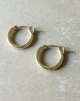 A pair of Becoming Jewelry Everyday Hoop Earrings, medium on a gray surface.