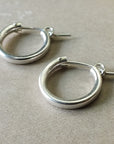 A pair of Becoming Jewelry Everyday Hoop Earrings, medium on a beige surface.