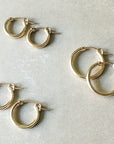 Six Becoming Jewelry Everyday Hoop Earrings, large on a gray surface.