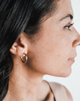 Profile of a woman with dark hair, wearing the large "Everyday Hoop Earrings" by Becoming Jewelry, looking to the right against a plain background.