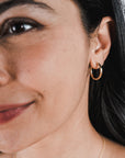 Close-up of a person's face in a light setting, showing their left eye, cheek, and part of their lips. They have black hair and are wearing a pair of large Everyday Hoop Earrings from Becoming Jewelry that add a touch of elegance to their everyday look.