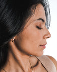 Profile of a woman with closed eyes and dark hair, adorned with Becoming Jewelry sterling silver small Everyday Hoop Earrings.