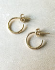 Dainty gold Open Hoop Earrings, small by Becoming Jewelry lying on a textured surface.