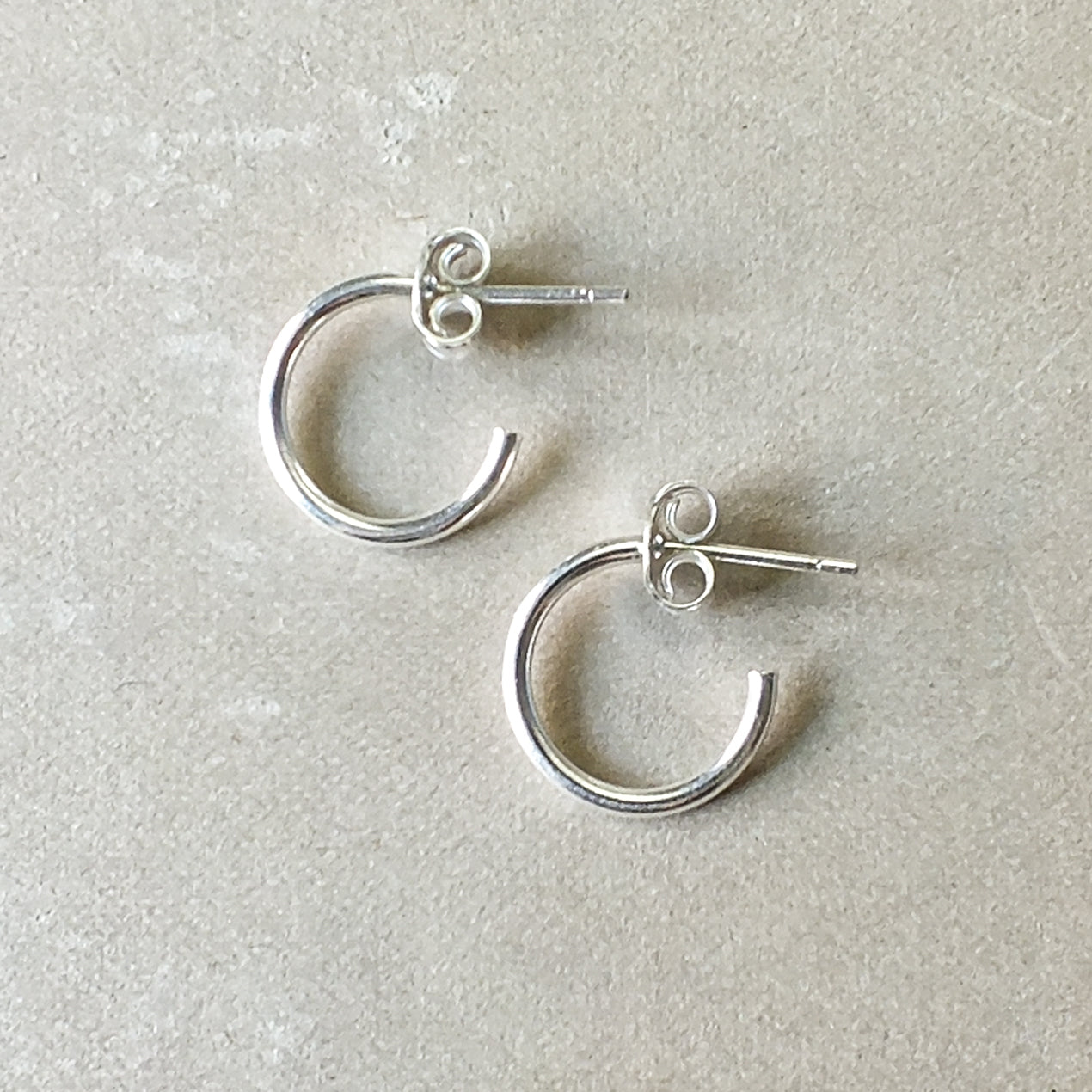 A pair of dainty Becoming Jewelry sterling silver Open Hoop Earrings, small on a gray background.