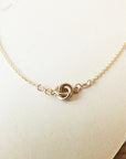 Love Knot Necklace by Becoming Jewelry with a knot pendant on a beige background.