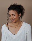 Woman wearing a white sweater against a brown background