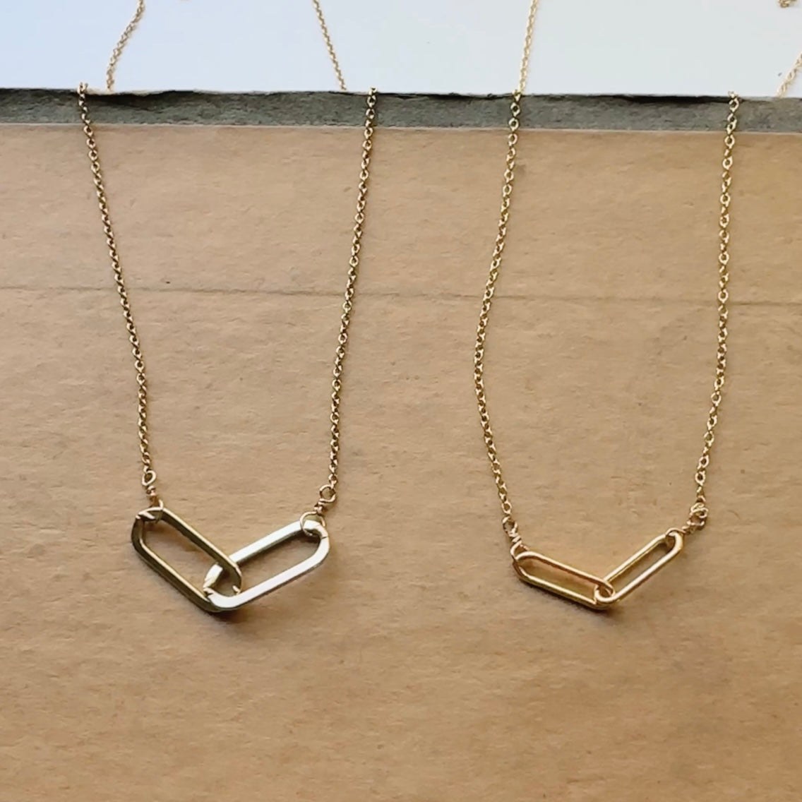 Two gold necklaces with unique links on a wooden surface