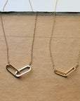 Two gold necklaces with unique links on a wooden surface
