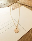 Be The Light Necklace with a Sunshine Charm pendant displayed on paper with lines by Becoming Jewelry.