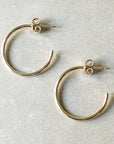 The large Open Hoop Earrings from Becoming Jewelry feature two simple hoops on a beige surface, with open ends and stud post backs. These lightweight earrings exemplify dainty jewelry.
