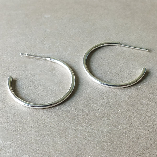 A pair of Becoming Jewelry sterling silver Open Hoop Earrings, large on a grey surface.