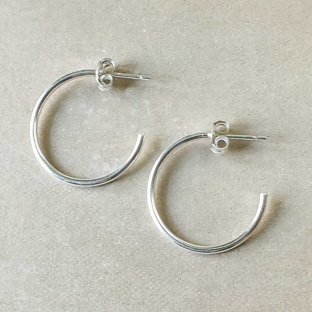 A pair of dainty silver Open Hoop Earrings, large by Becoming Jewelry on a light background.