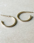 A pair of medium-sized, dainty Becoming Jewelry Open Hoop Earrings on a gray surface.