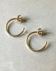 A pair of lightweight, classic medium Open Hoop Earrings with post backs from Becoming Jewelry is displayed on a light textured surface.
