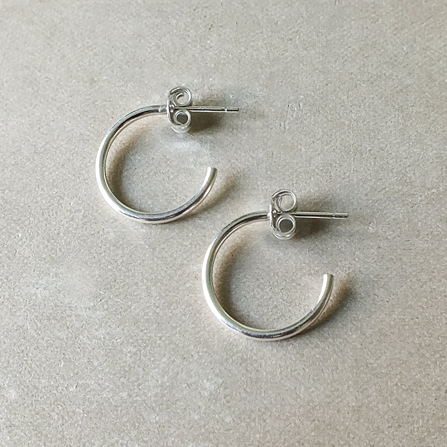 Open hoop earrings, medium from Becoming Jewelry on a light grey surface.
