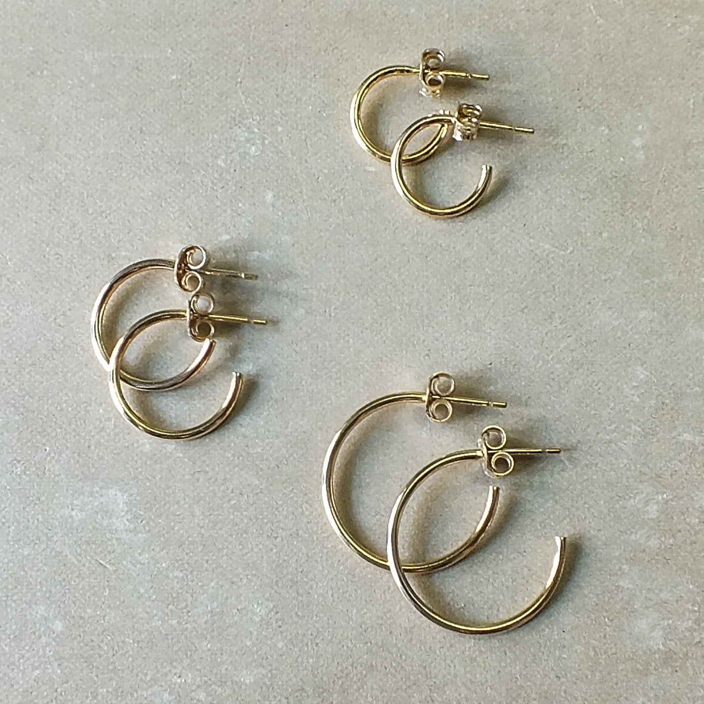A set of four Becoming Jewelry Open Hoop Earrings, medium on a gray background.