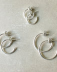 Four pairs of Open Hoop Earrings, large, by Becoming Jewelry in silver, varying in size, displayed on a light gray background. Perfect for those who appreciate dainty jewelry.