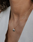 Necklace with a pendant worn by a person in a light-colored outfit