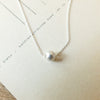 Simplify Necklace with a single pearl pendant on a display card by Becoming Jewelry.
