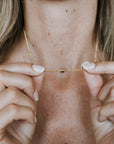 Someone holding a delicate Stick Together Necklace from Becoming Jewelry with both hands, highlighting the small barrel clasp at the center.