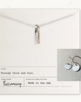 The Through Thick & Thin Necklace + Earrings Set by Becoming Jewelry features silver and gold vertical bars on a card with an image of matching mixed metal earrings. Made in the USA.