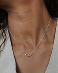 Necklace with a small pendant worn by a person in a light-colored top.